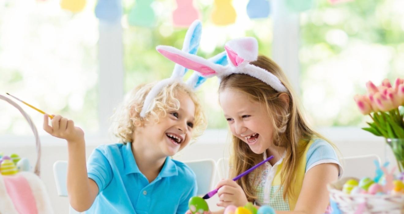 picture of happy children wearing bunny ears painting easter eggs