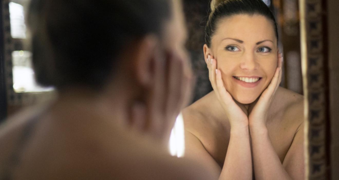 picture of a happy woman looking at herself in the mirror