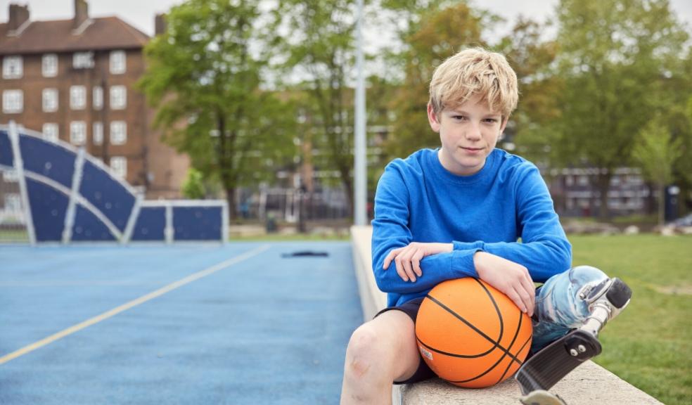 picture of a boy sat on a wall with a basketball