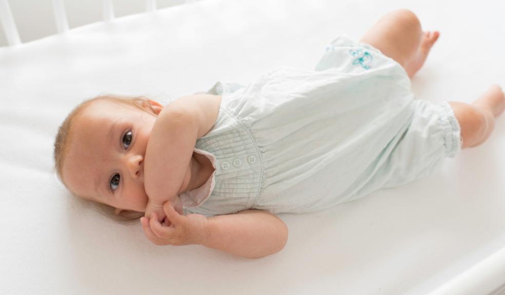 picture of a happy baby laying on a Hippychick fitted bedsheet