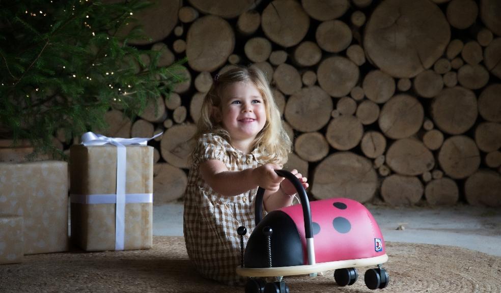 a happy child at Christmas playing with a laybug wooden ride on toy picture of a happy child at Christmas playing with a laybug wooden ride on toy