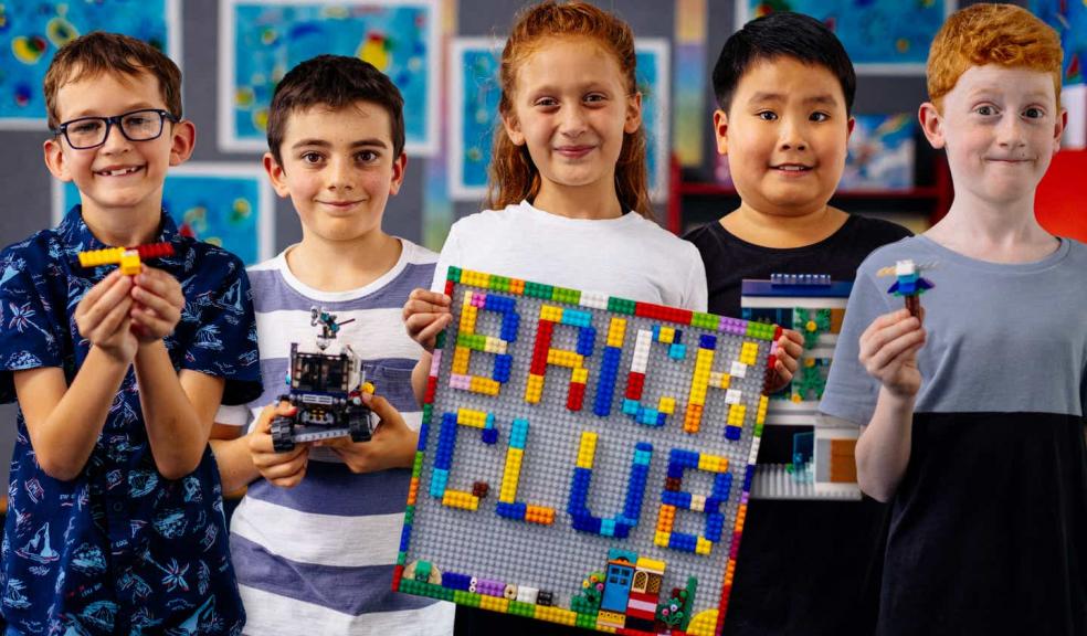 A picture of a diverse group of children with their lego brick club sign