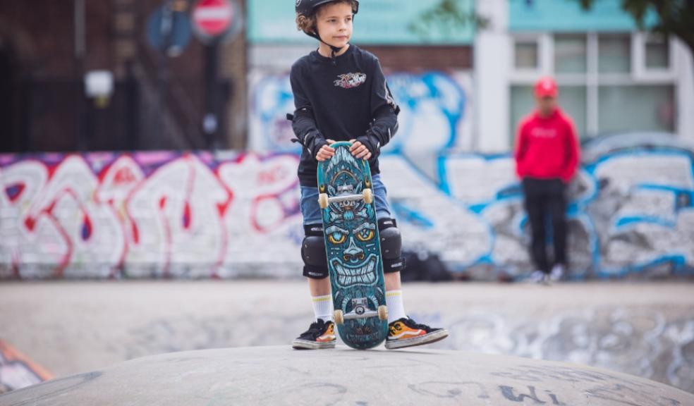 a child with a skateboard and helmet at a skatepark picture of a child with a skateboard and helmet at a skatepark