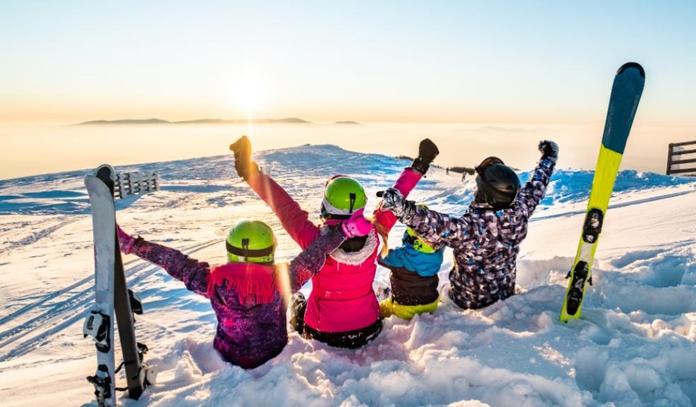 picture of a family on a ski holiday sitting in the snow looking at the sun set