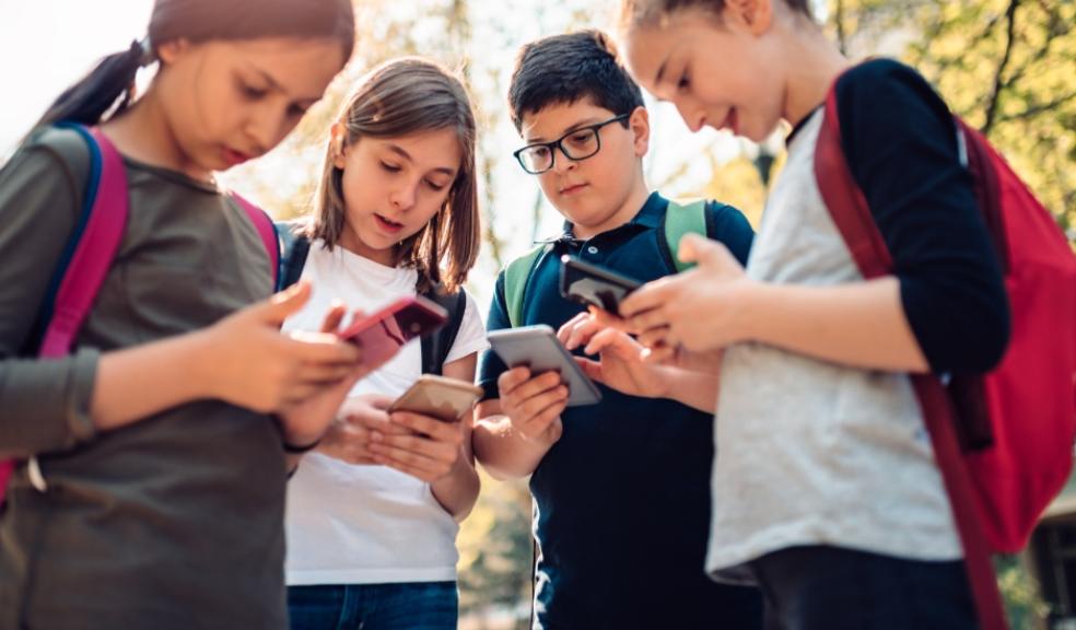 a group of children outside looking at their smartphones picture of a group of children outside looking at their smartphones