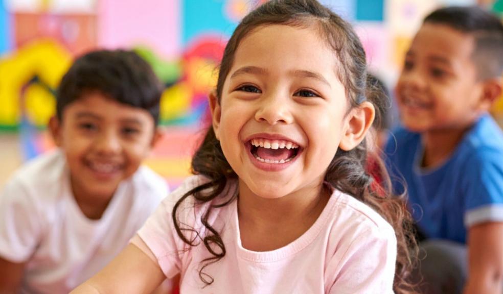 picture of a happy child in a classroom with other happy children behind her