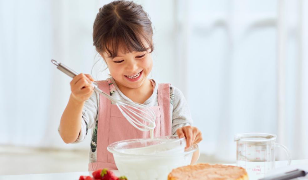 picture of a happy child mixing some cake mixture in a white kitchen