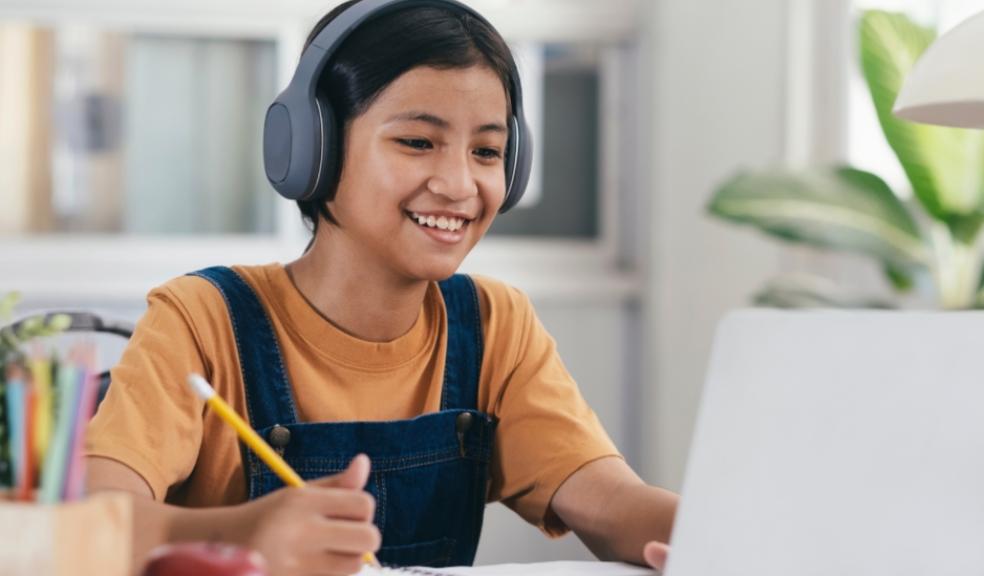 picture of a happy child wearing headphones and using a laptop for online learning