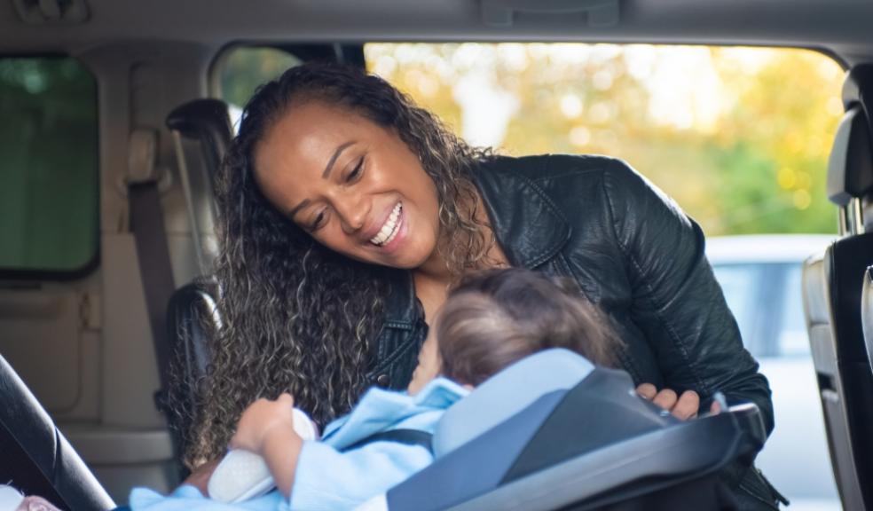a happy mum putting her child into a rear facing carseat in the car to keep them safe picture of a happy mum putting her child into a rear facing carseat in the car to keep them safe