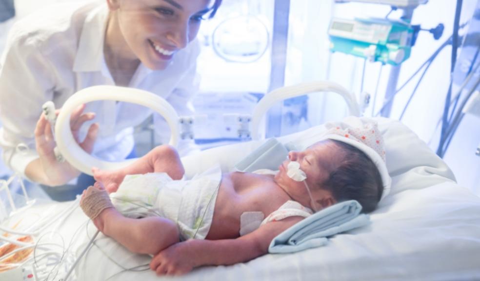 a happy neonatal nurse looking in on a baby with Meconium Aspiration Syndrome picture of a happy neonatal nurse looking in on a baby with Meconium Aspiration Syndrome