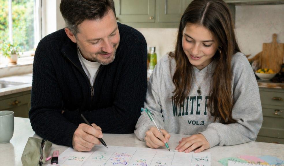 Dad helping his teenage daughter create a revision timetable at a kitchen island in a bright family home picture of Dad helping his teenage daughter create a revision timetable at a kitchen island in a bright family home