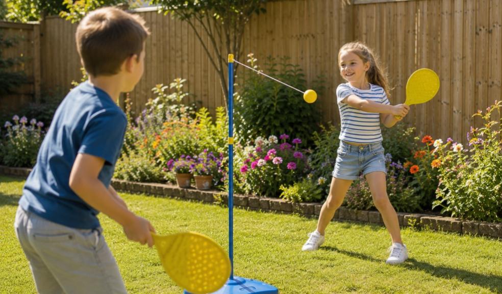 Two happy children playing Swingball in a secure family garden with colourful flower beds and wooden fencing picture of Two happy children playing Swingball in a secure family garden with colourful flower beds and wooden fencing