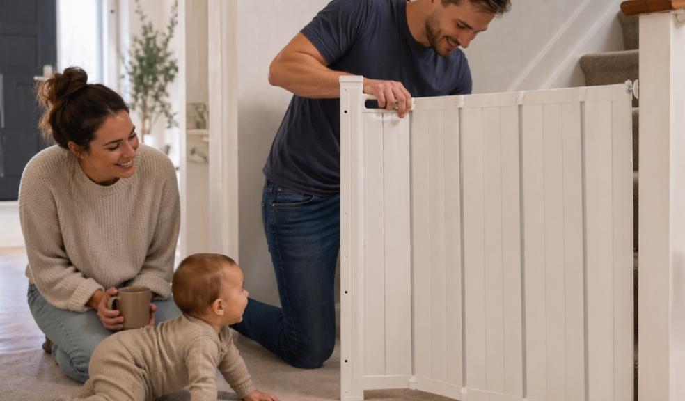picture of Dad fitting a stair gate while a mum and crawling baby watch nearby in a family home, showing babyproofing and home safety in action