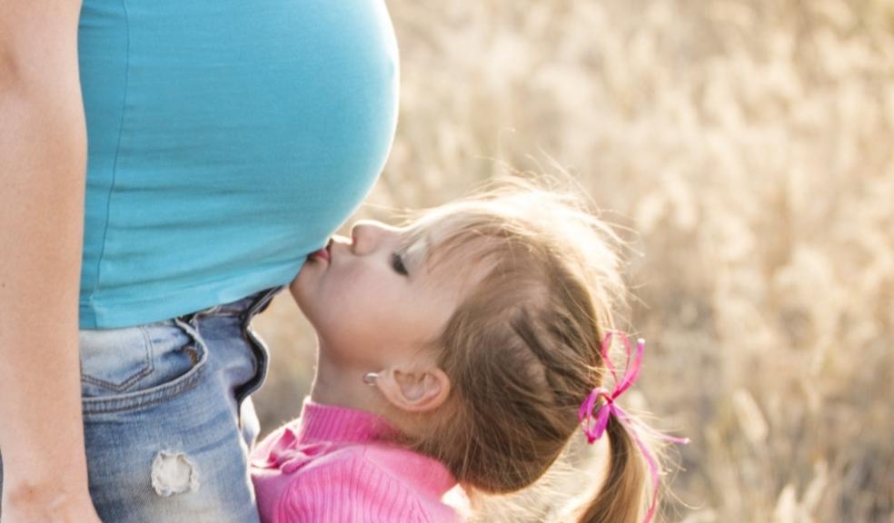 Daughter kissing her mum's pregnant belly