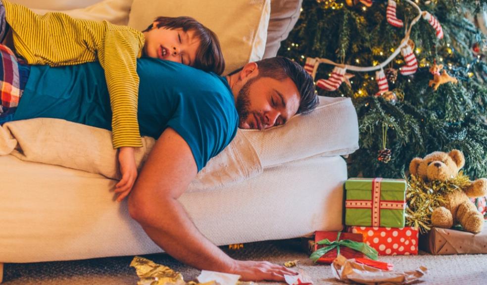 picture of a Father and son asleep on the sofa suffering Christmas burnout