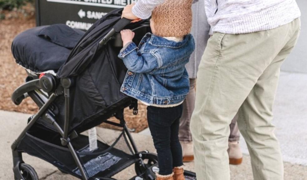 picture of parent using a lascal buggy board to walk toddler and baby to school