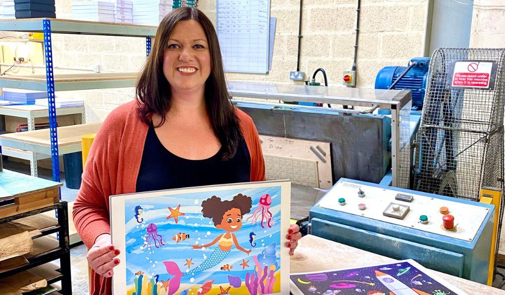 Founder of Play Shed Puzzles, Jacqueline Buckland is in the jigsaw factory holding a mermaid puzzle 