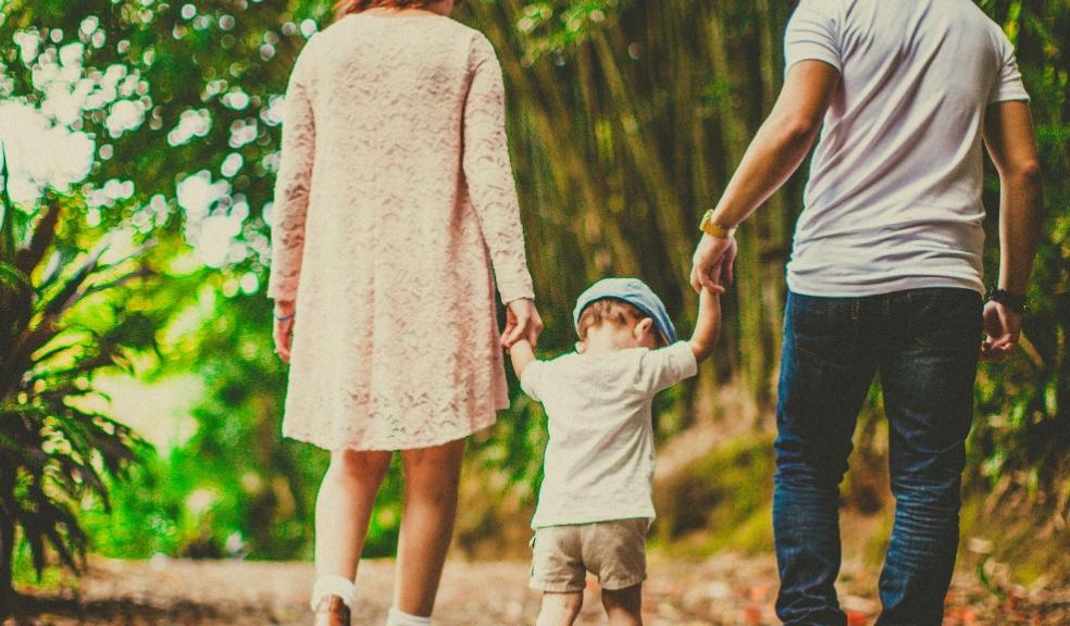 picture of parents walking through a wood holding their childs hand