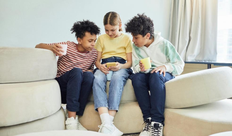 picture of three children sat together looking at a smartphone