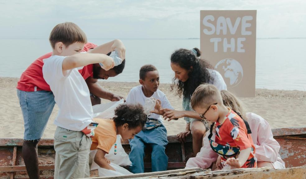 picture of children cleaning a beach with a save the planet sign in the background