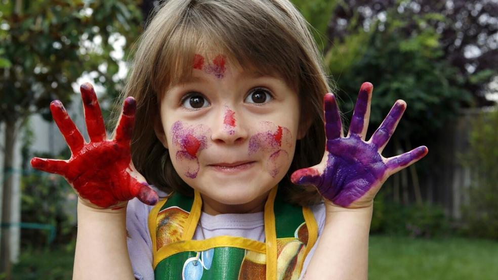 picture of a happy girl with paint on her hands and face