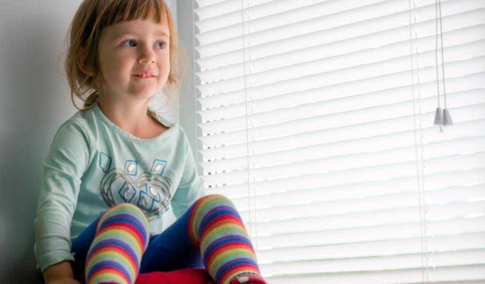 picture of Toddler sat next to window blinds