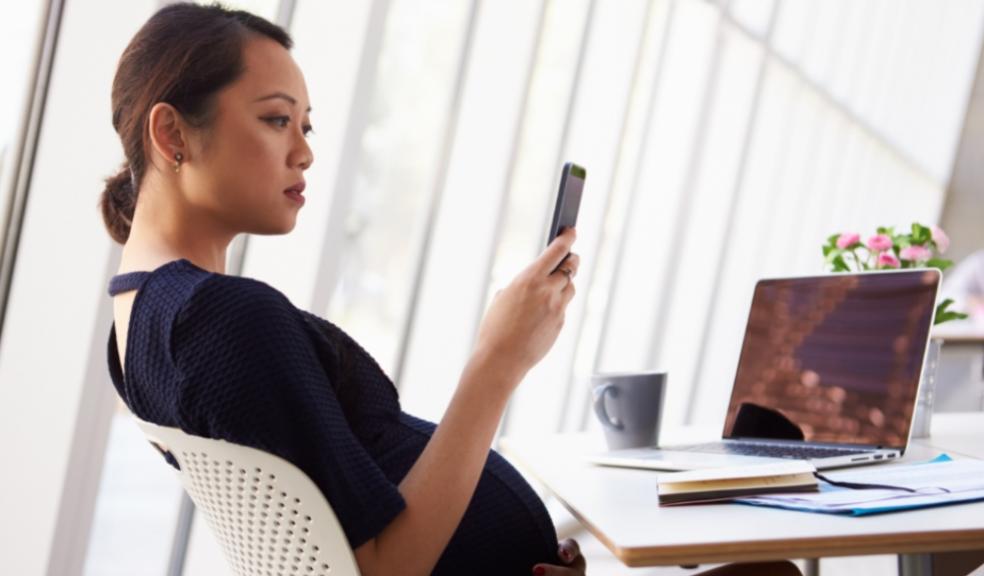Picture of a pregnant woman reading a text message on her smart phone