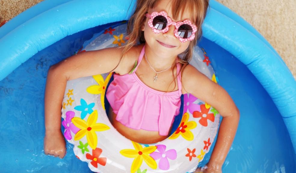 Child laying in a rubber ring in a paddling pool