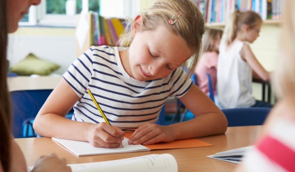 Picture of a school child sat working at a desk in a school classroom