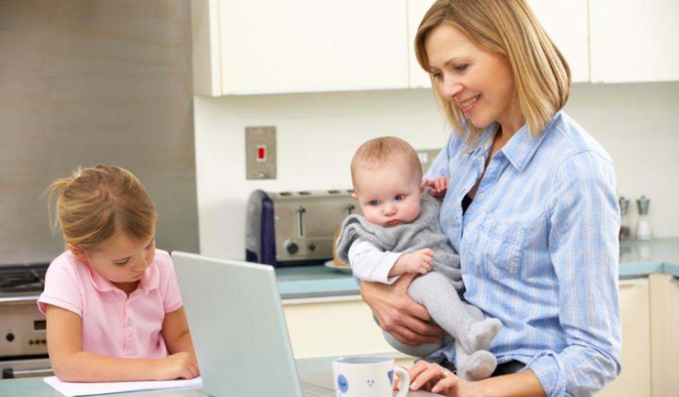 Picture of a mum on a laptop with her children in the kitchen