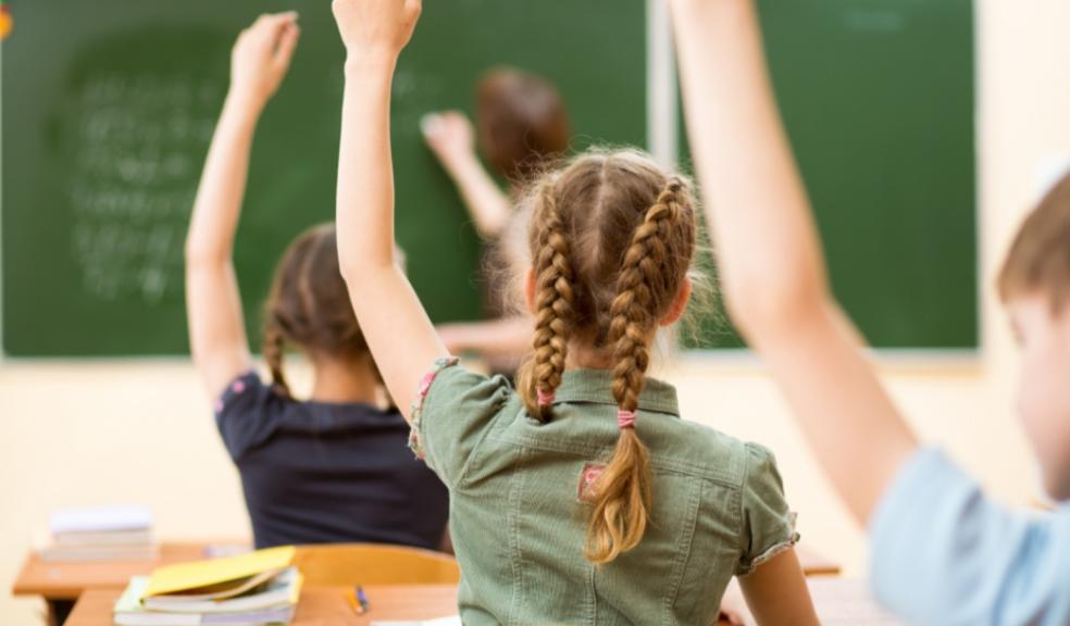 Picture of children putting their hands up in class