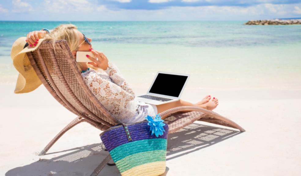 Picture of a business woman working on a beach with her phone and laptop