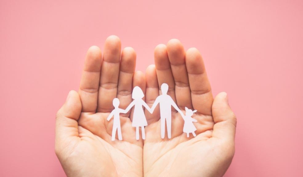 Hand holding family paper cut on pink background. Family day concept
