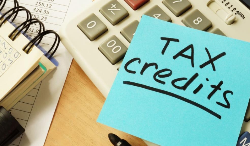 Picture of Tax credits written on a post it note with a calculator and notebook