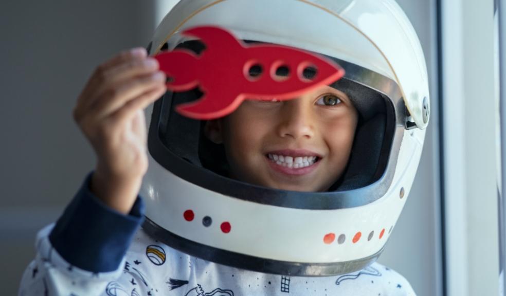 picture of a child dresses as a astronaut holding a toy rocket