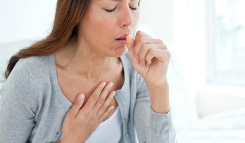 picture of an unwell woman coughing into her hand