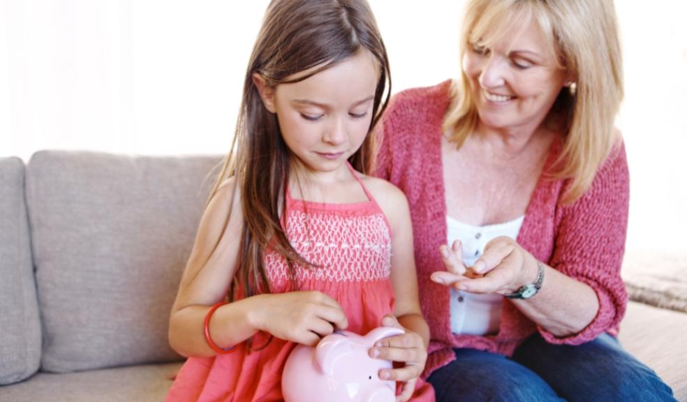 picture of a happy mum giving her daughter pocket money to put in a piggy bank