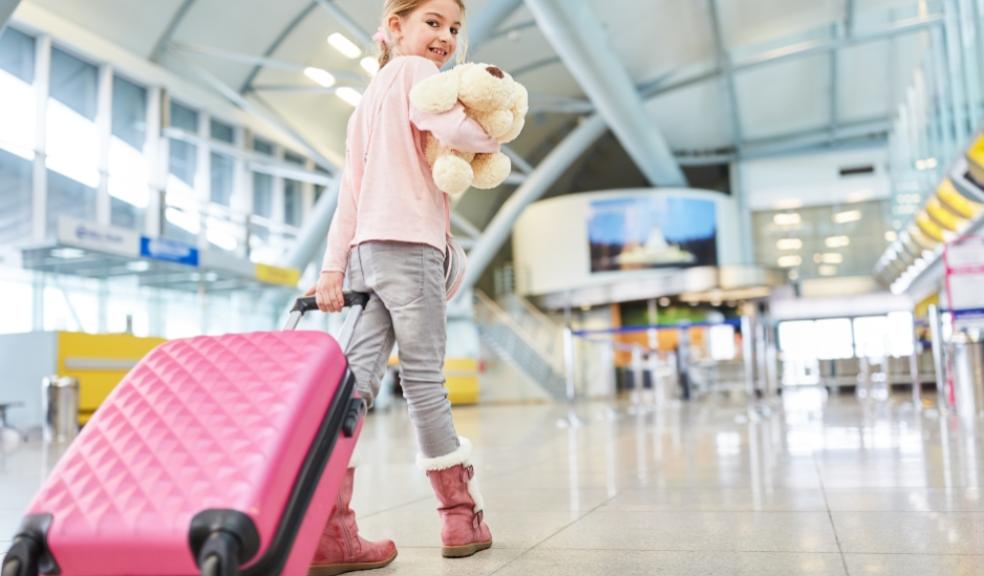 picture of a child in an airport with a suitcase and teddy bear
