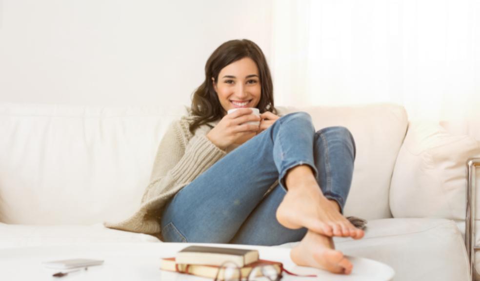 picture of a woman relaxing on the sofa with a drink and book