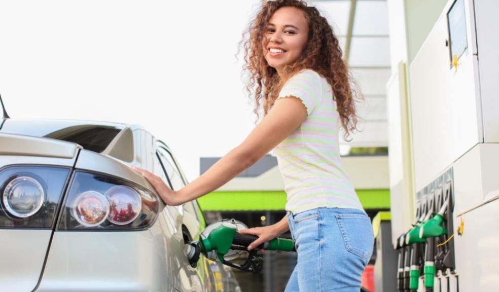 picture of an african american woman putting fuel in a car