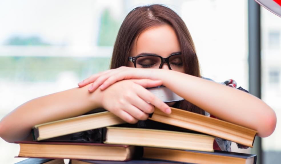 picture of a teen falling asleep on a pile of books