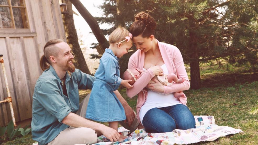 picture of newborn baby and family outside on a picnic blanket