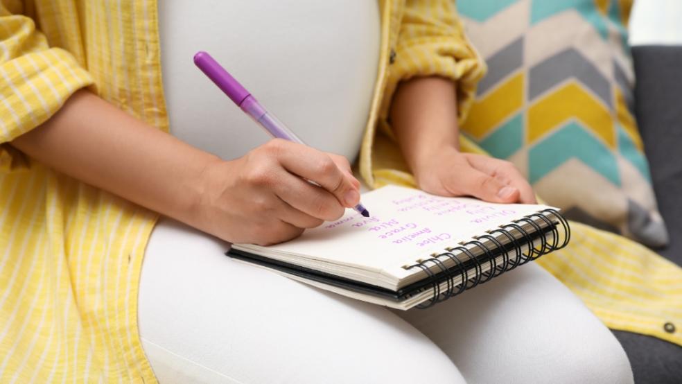 picture of pregnant woman writing a list of baby names