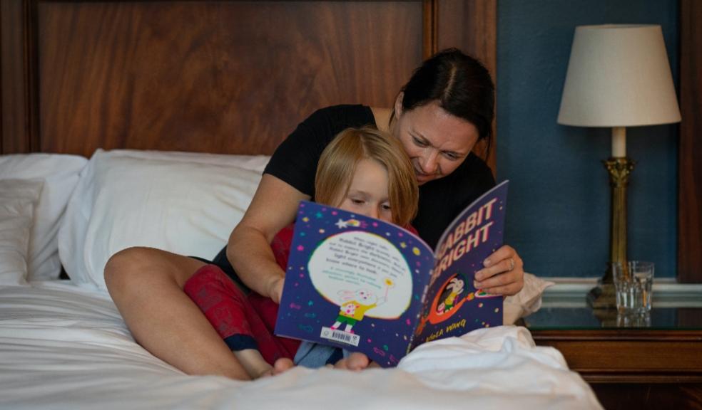 picture of a mum reading a child a bedtime story on a bed
