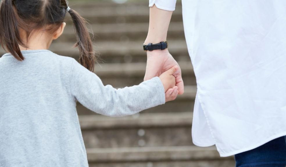 picture of a child holding hands and walking outside with her parent