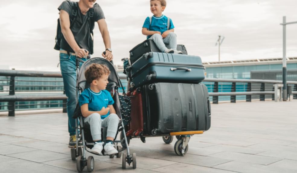 picture of a dad at an airport with his two children and lots of suitcases moving abroad