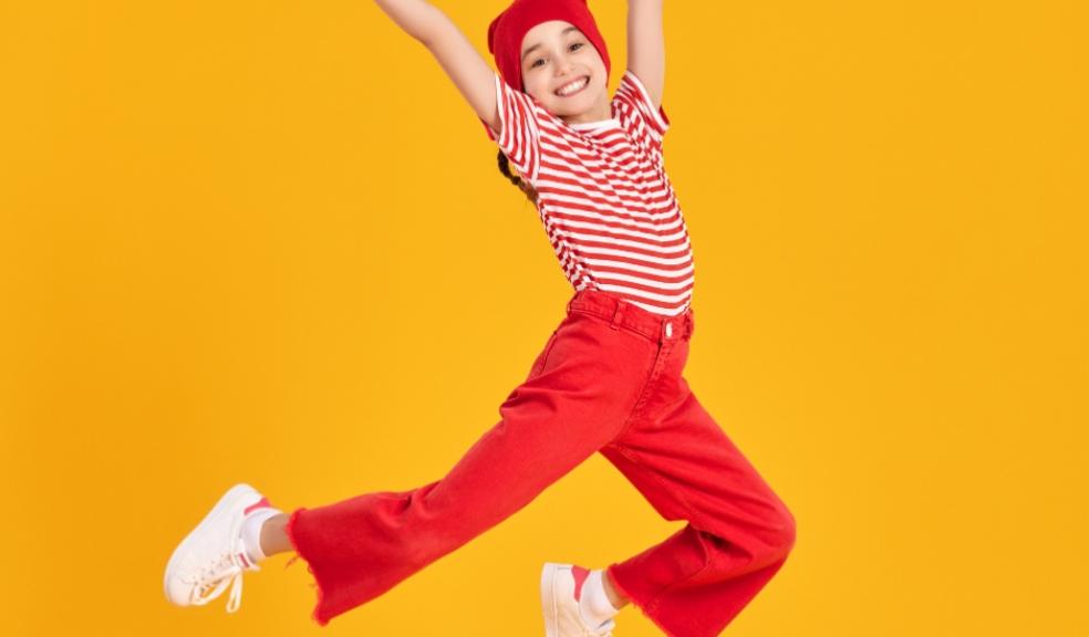 picture of a happy emotionally resilient child wearing red and jumping in the air