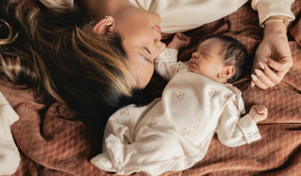 picture of a mum laying with her newborn baby on a brown blanket