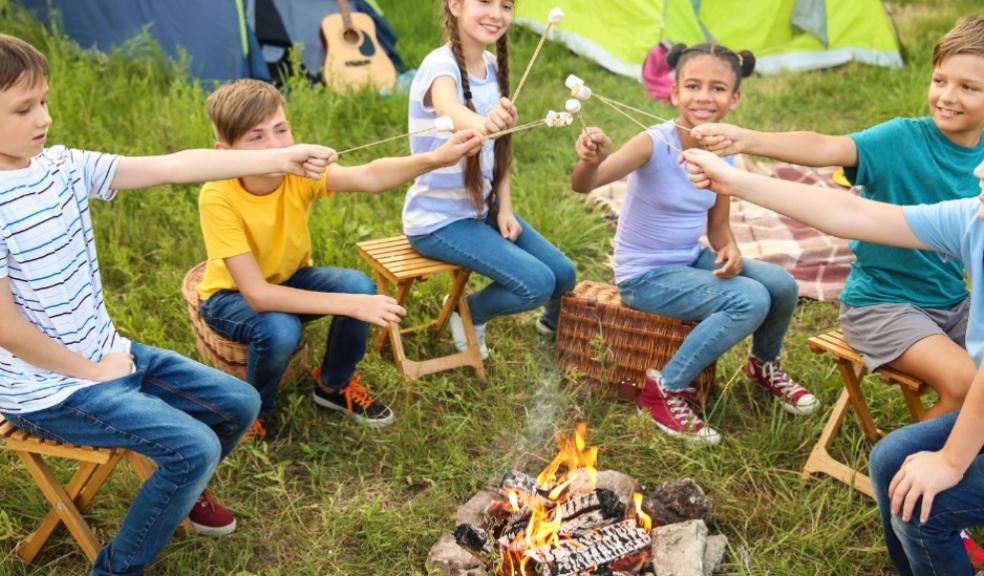 picture of children sat round a camp fire toasting marshmallows at a summer camp