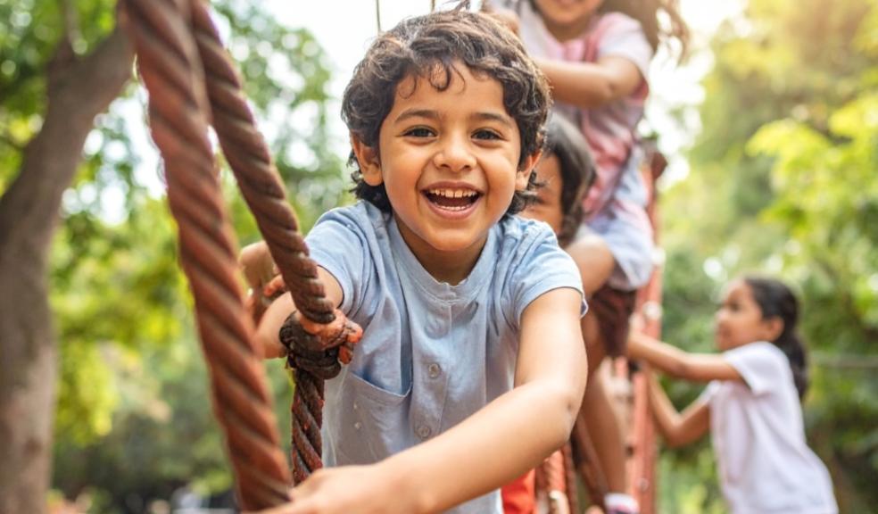 picture of happy resilient children playing on a rope bridge together in a park